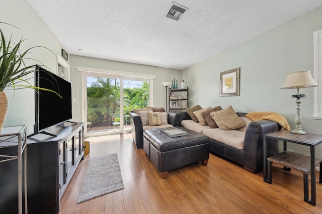 living area featuring a textured ceiling, visible vents, and wood finished floors