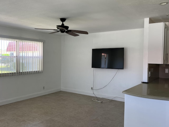 unfurnished living room with baseboards and a ceiling fan