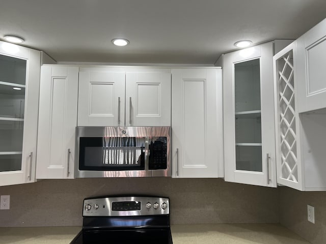 kitchen with glass insert cabinets, appliances with stainless steel finishes, and white cabinetry