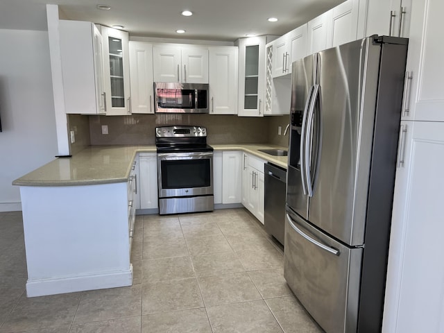 kitchen with glass insert cabinets, light tile patterned floors, decorative backsplash, appliances with stainless steel finishes, and white cabinetry