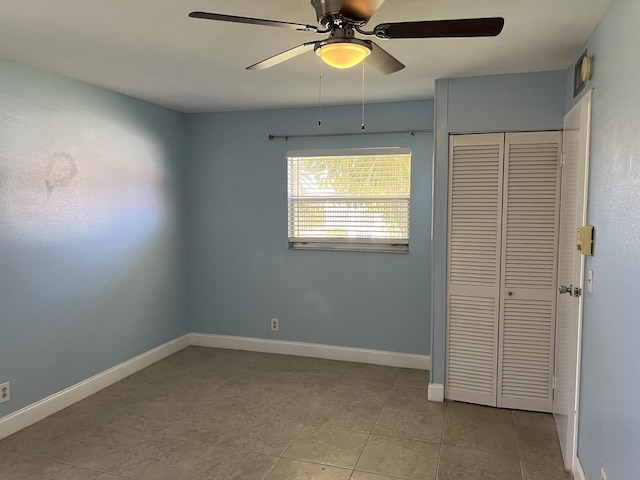 unfurnished bedroom featuring a closet, ceiling fan, tile patterned floors, and baseboards