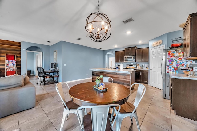 dining area with an inviting chandelier, visible vents, light tile patterned floors, and arched walkways