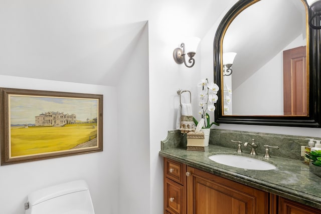 half bathroom with lofted ceiling, vanity, and toilet