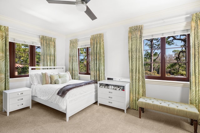 bedroom with crown molding, ceiling fan, and light colored carpet