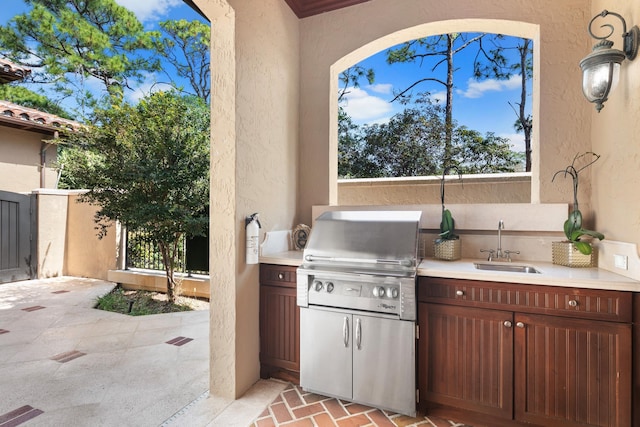 view of patio / terrace featuring a sink, an outdoor kitchen, a grill, and fence