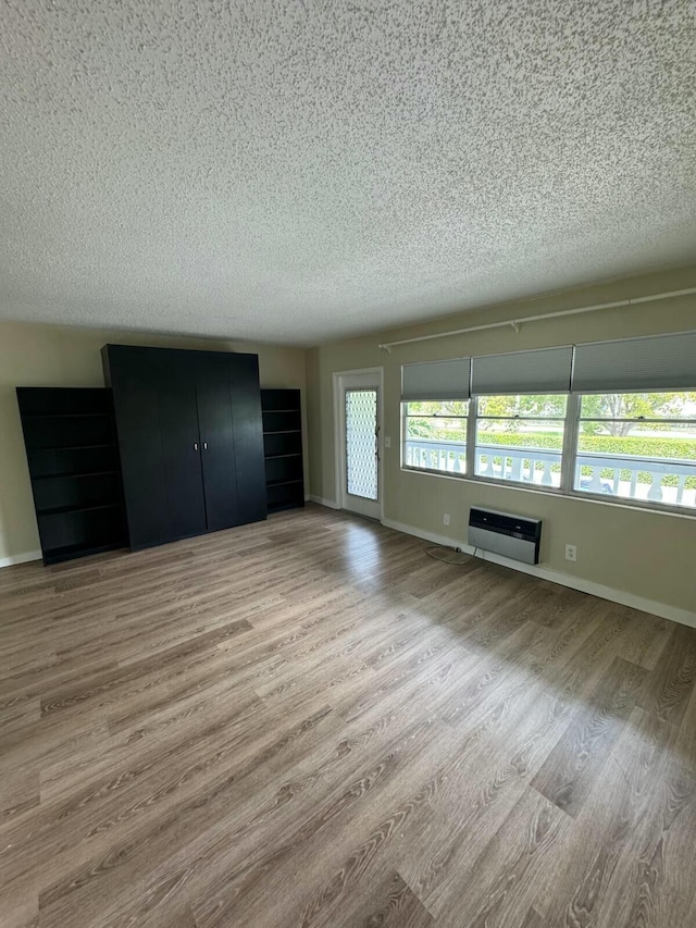 unfurnished bedroom with a textured ceiling, baseboards, and wood finished floors