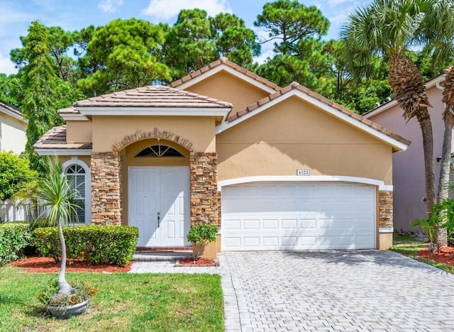 mediterranean / spanish-style home with stone siding, decorative driveway, and stucco siding