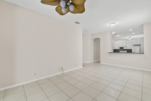 unfurnished living room with arched walkways, visible vents, and baseboards