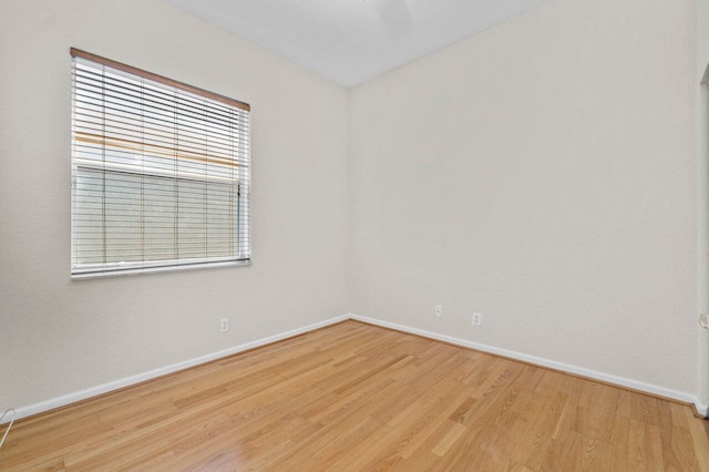 spare room featuring baseboards and wood finished floors