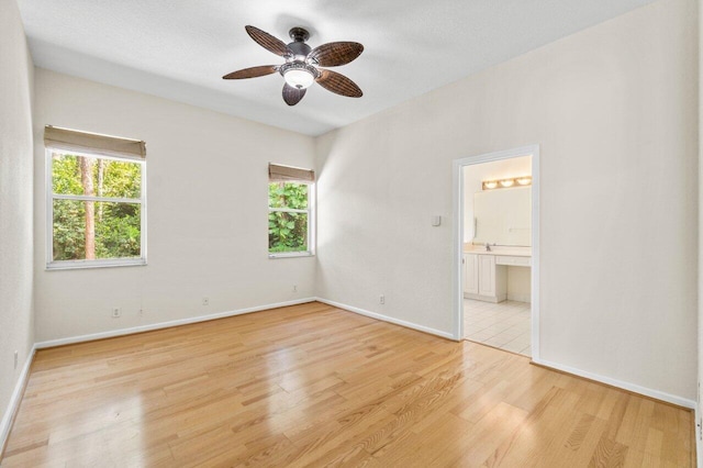 spare room with light wood-style flooring, a wealth of natural light, and baseboards