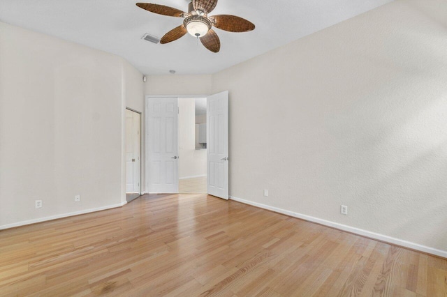 empty room featuring light wood-type flooring, visible vents, ceiling fan, and baseboards