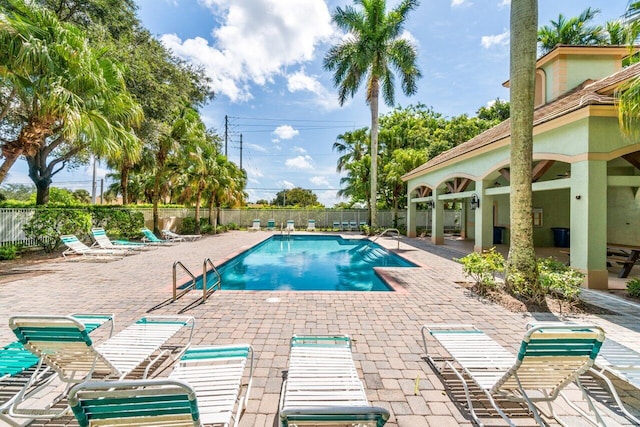 community pool with fence and a patio