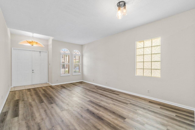 foyer featuring a textured ceiling, wood finished floors, and baseboards