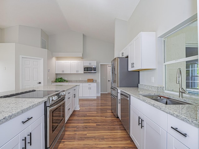 kitchen with white cabinets, light stone counters, stainless steel appliances, and a sink