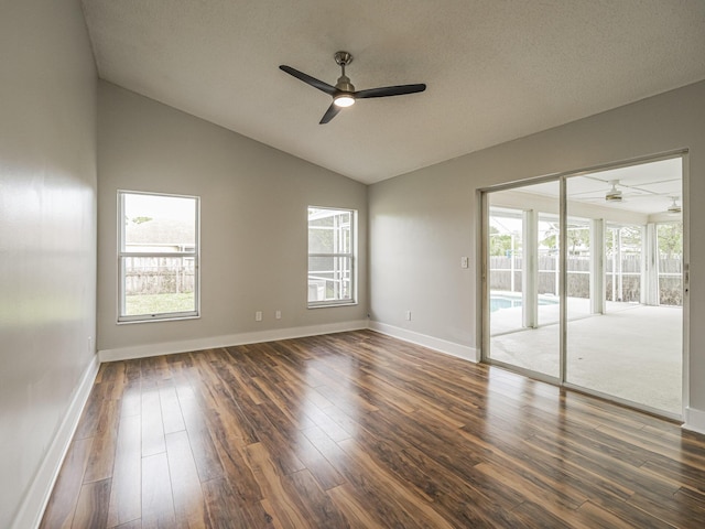 empty room featuring vaulted ceiling, dark wood-style flooring, a ceiling fan, and baseboards