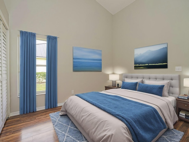 bedroom featuring high vaulted ceiling, baseboards, and wood finished floors