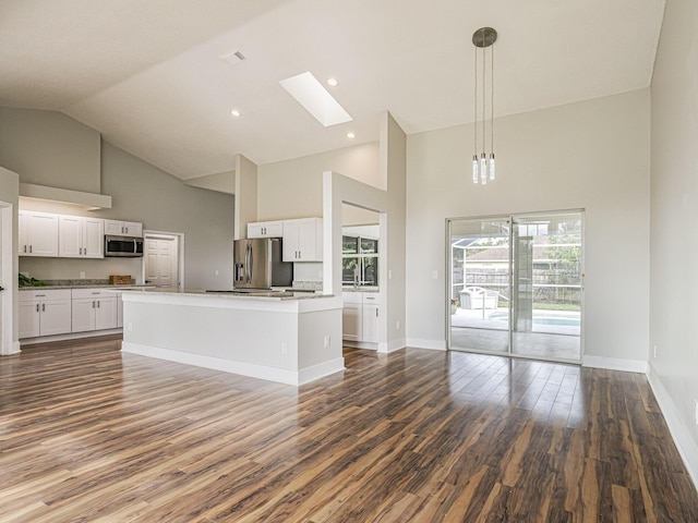 kitchen featuring open floor plan, stainless steel appliances, dark wood finished floors, and white cabinetry