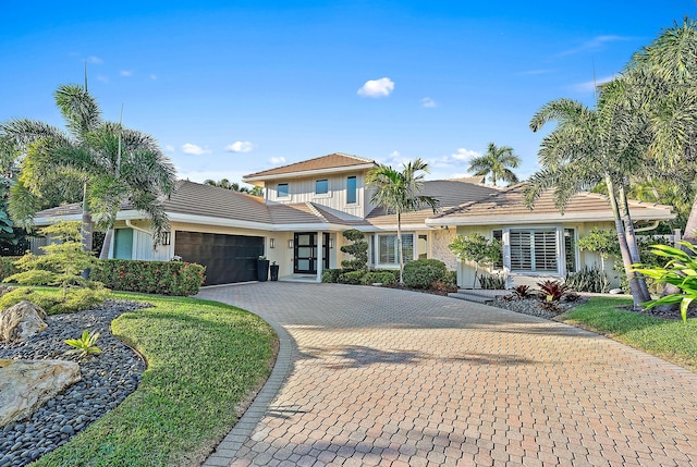 view of front of house featuring a tiled roof, decorative driveway, and an attached garage