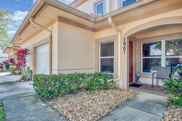 doorway to property featuring an attached garage and stucco siding