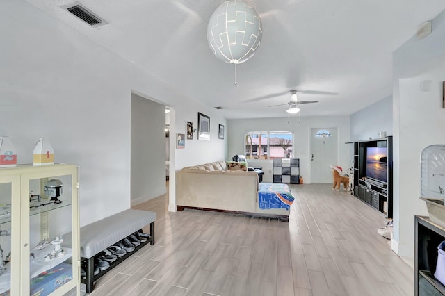 living area featuring light wood-type flooring, visible vents, and a ceiling fan