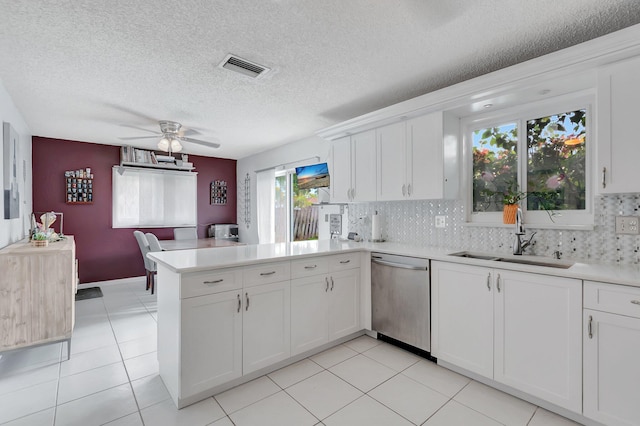 kitchen featuring a peninsula, a sink, visible vents, light countertops, and stainless steel dishwasher