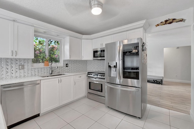 kitchen featuring white cabinets, decorative backsplash, stainless steel appliances, light countertops, and a sink