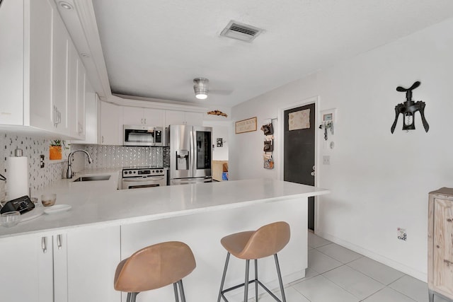 kitchen featuring appliances with stainless steel finishes, light countertops, a sink, and backsplash