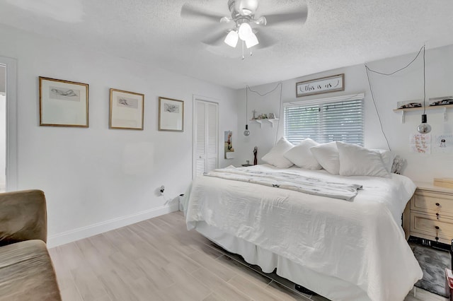 bedroom featuring a closet, baseboards, light wood-style flooring, and a textured ceiling