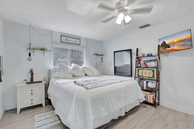 bedroom with wood finish floors, visible vents, ceiling fan, a textured ceiling, and baseboards