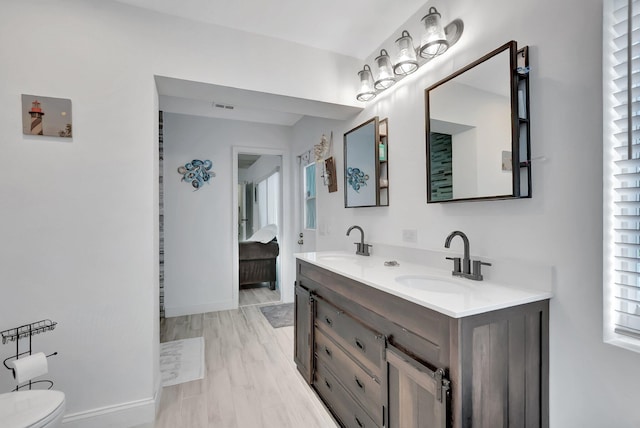 bathroom with visible vents, double vanity, a sink, and toilet