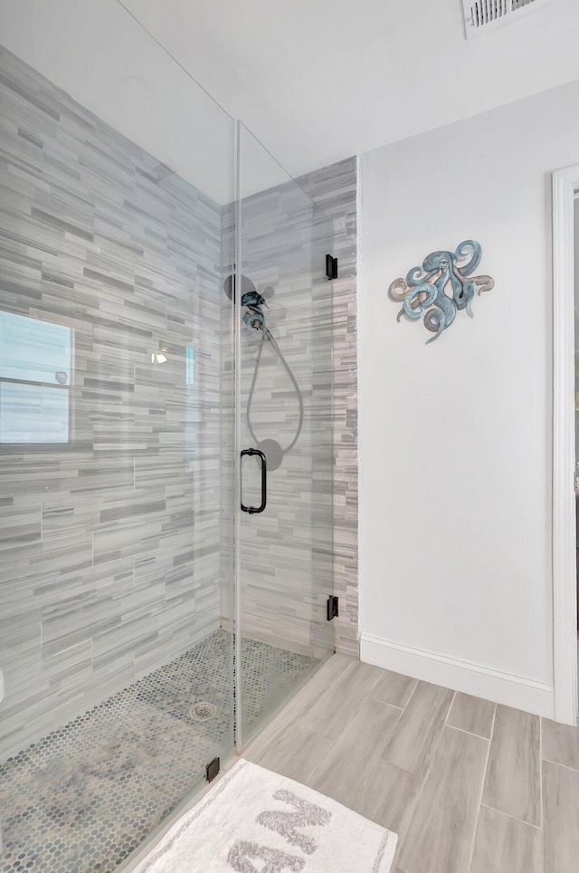 bathroom with a shower stall, visible vents, and baseboards