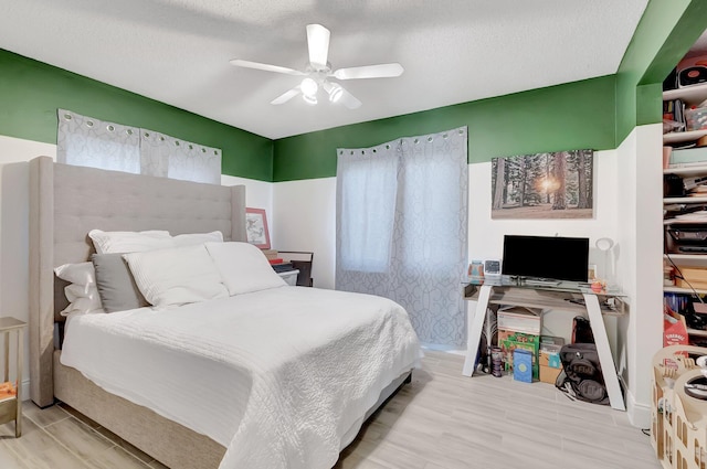 bedroom with a textured ceiling, wood finished floors, and a ceiling fan