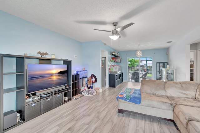 living room featuring a textured ceiling, ceiling fan, and wood finished floors