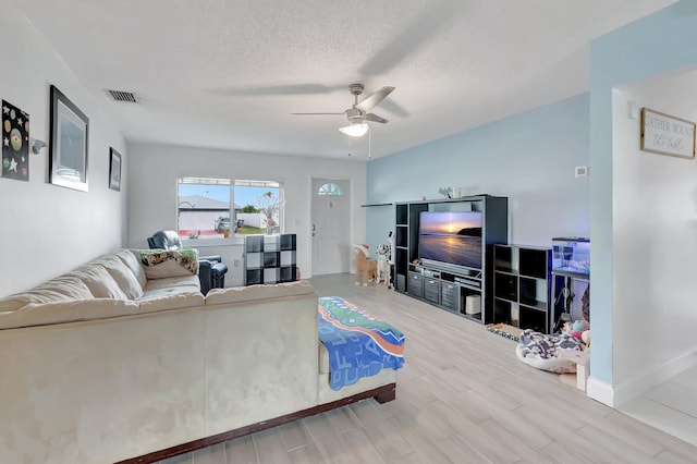 living room featuring a textured ceiling, wood finished floors, visible vents, baseboards, and a ceiling fan