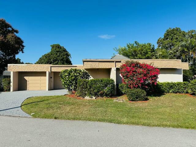 view of front of home featuring a front yard, decorative driveway, and an attached garage