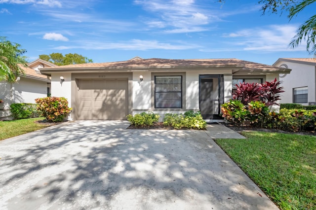 view of front of property featuring a front yard, driveway, an attached garage, and stucco siding