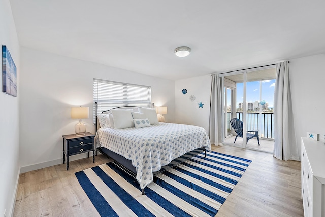 bedroom featuring baseboards, multiple windows, light wood-style floors, and access to outside