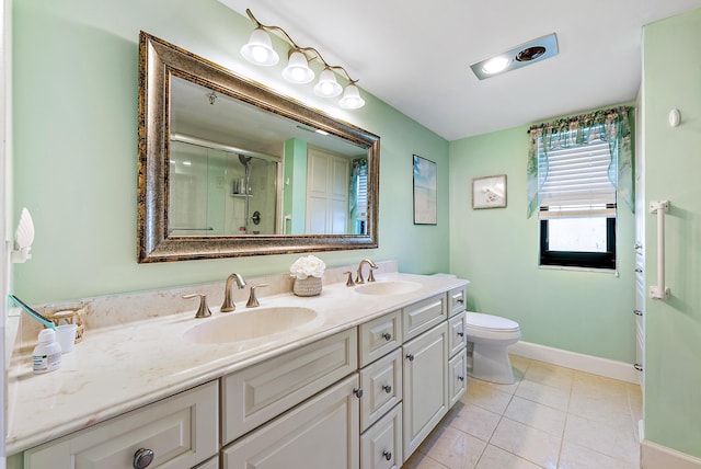full bath featuring a sink, double vanity, a stall shower, and baseboards