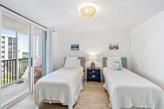 bedroom with a water view, access to outside, and light wood-style flooring