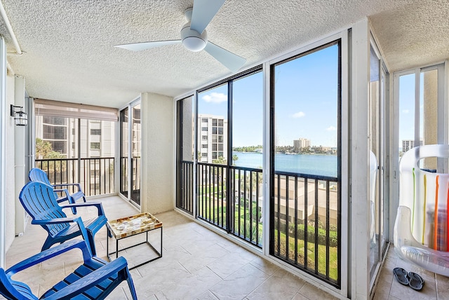 sunroom featuring a textured ceiling, a water view, expansive windows, and a healthy amount of sunlight