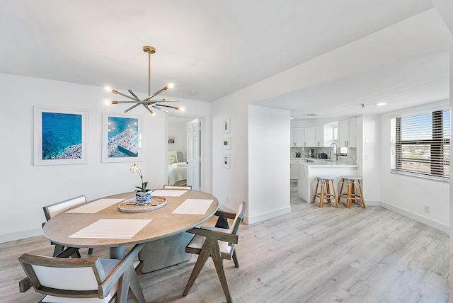 dining room with baseboards, an inviting chandelier, and light wood-type flooring