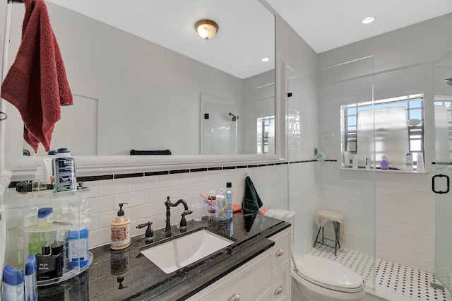 bathroom with tile walls, backsplash, toilet, a shower stall, and vanity