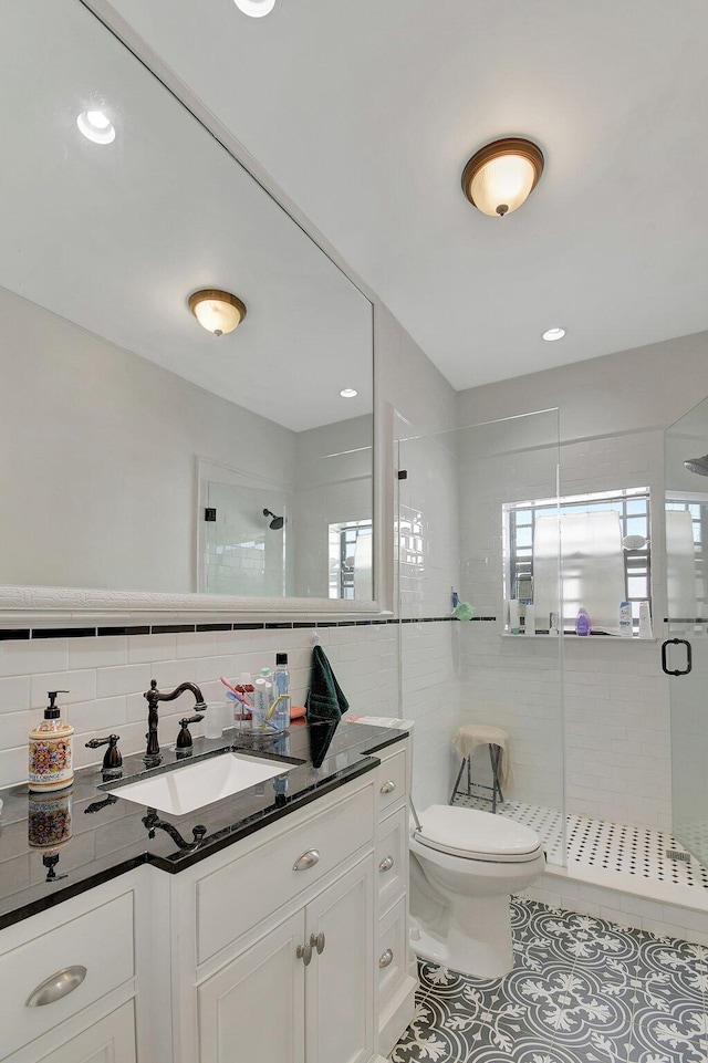 full bathroom featuring tile walls, toilet, vanity, a shower stall, and tile patterned floors