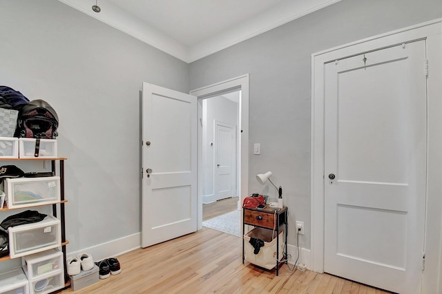 interior space with crown molding, light wood-style flooring, and baseboards