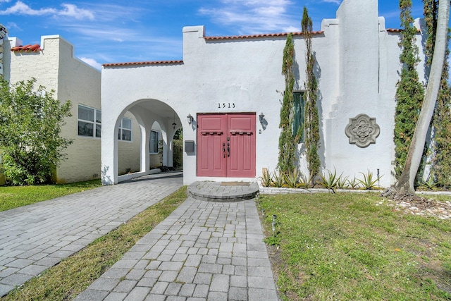 entrance to property with a tile roof and stucco siding