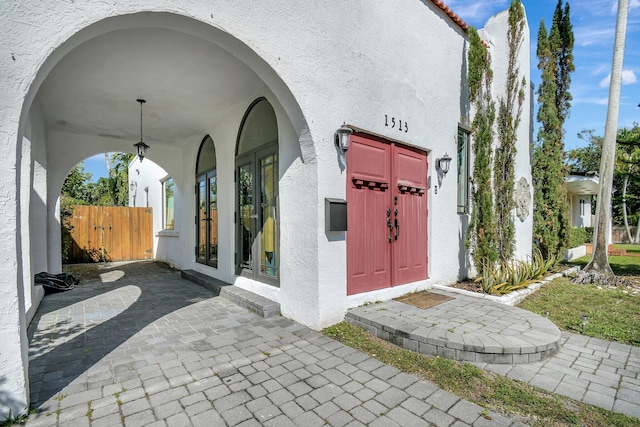 property entrance with a tiled roof, fence, french doors, and stucco siding