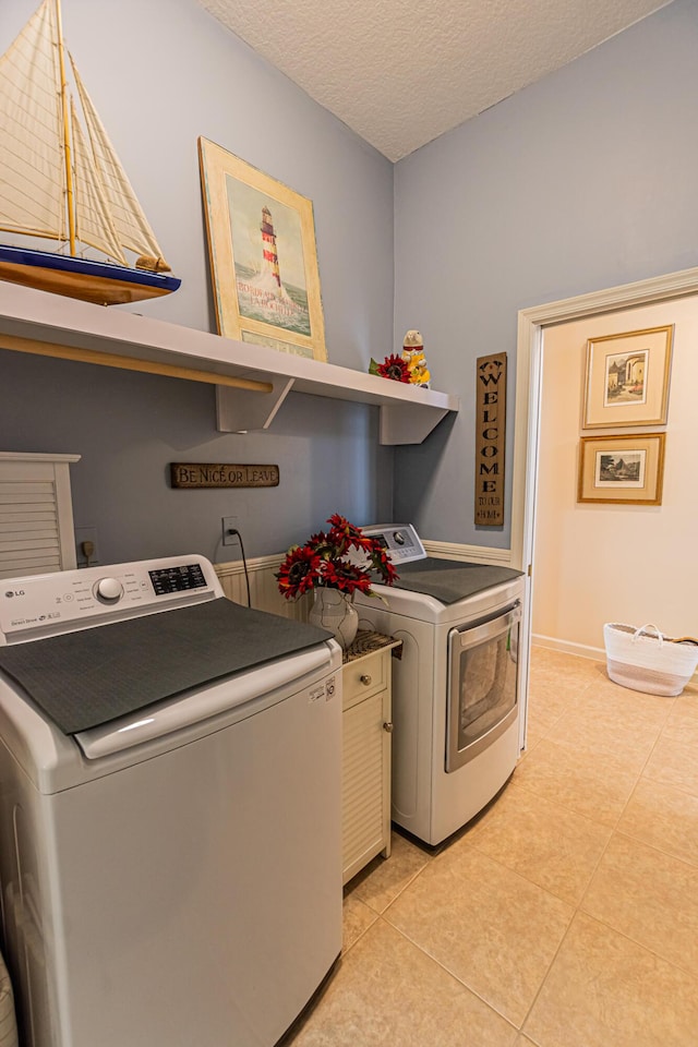 laundry room with a textured ceiling, laundry area, light tile patterned floors, and washer and dryer