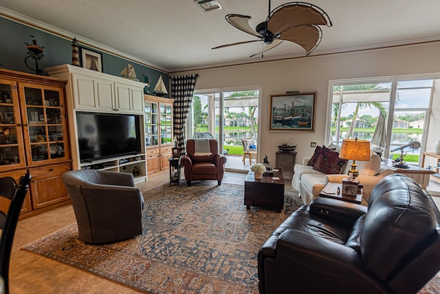 living area featuring a ceiling fan, ornamental molding, a textured ceiling, and tile patterned floors