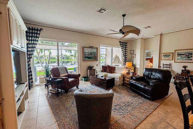 living room featuring a ceiling fan, visible vents, a textured ceiling, and light tile patterned floors