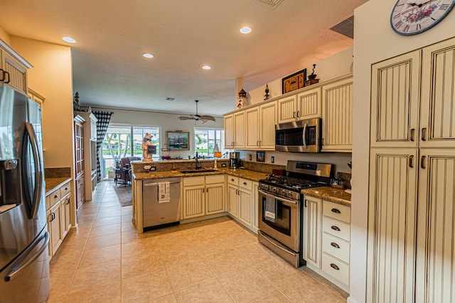 kitchen featuring cream cabinetry, recessed lighting, appliances with stainless steel finishes, a sink, and a peninsula